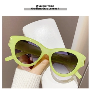 Close-up of avocado green thick frame sunglasses with gradient grey lenses and white hard case