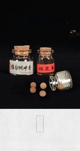 Detailed view of handmade brown incense pills in a clear glass bottle with cork stopper