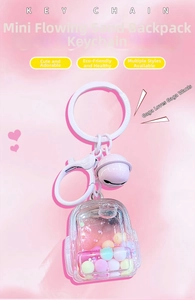 Close-up of a liquid quicksand backpack keychain with pink glitter and a small bell