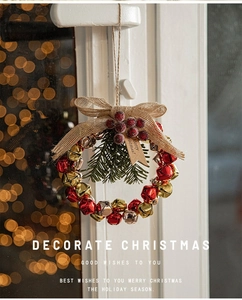 Close-up of Christmas bell wreath with burlap bow and red berries on bokeh background
