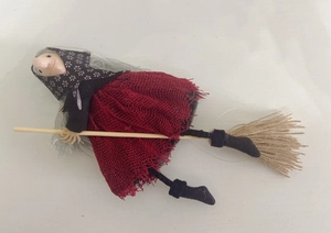 Detail of a handmade witch doll on a wooden broomstick for Halloween party decor