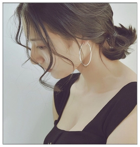Detalle de pendientes de aro grandes de 6cm de acero inoxidable en una modelo mujer