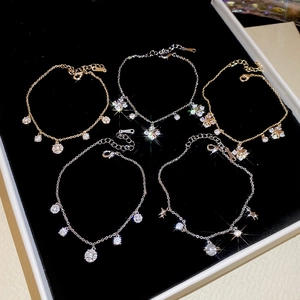Detail of delicate gold and silver bracelets with Saturn, star, and zircon charms