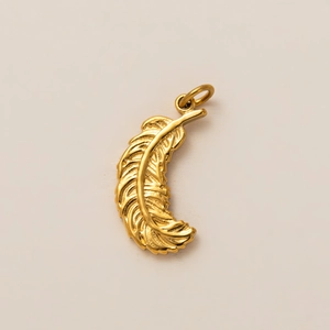 Detailed macro view of an 18k gold plated feather pendant with fine metallic textures