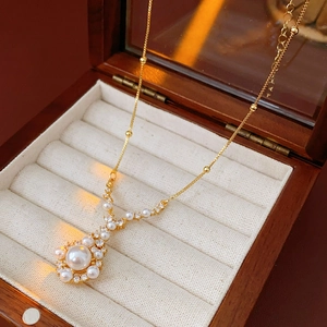 Close-up of gold plated teardrop pendant with pearls and zircons in a wooden jewelry box