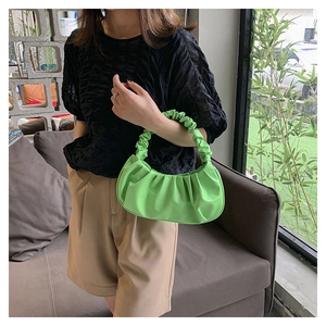 Detailed close-up of a green cloud-style ruched handbag shown on a female model