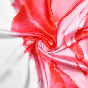 Gros plan sur un tissu tie-dye rouge et blanc au lustre soyeux et au drapé fluide