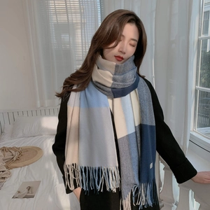 Detail of soft blue and beige plaid cashmere-like scarf with fringe on female model