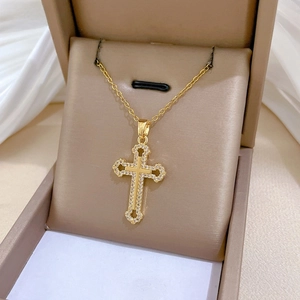 Close-up of gold hollow cross necklace with sparkling crystals in a beige display box