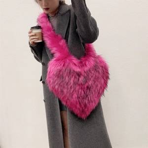 Close-up of bright pink faux fur heart-shaped crossbody bag worn on a winter coat