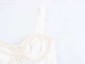Dettaglio di un vestito bianco con intricato design di nodi in corda intrecciata sul busto
