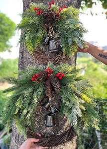 Outdoor detail of Christmas wreaths with pine needles, red berries and vintage metal bells