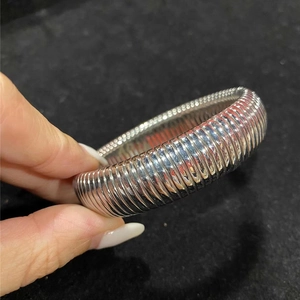 Dettaglio del bracciale Tubogas argento con trama a spirale sulla fascia larga d'acciaio