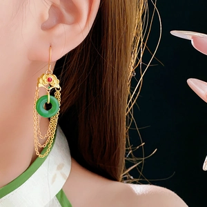 Detailed close-up of Chinese style gold-plated lotus earrings with green jade-like ring and tassels