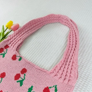 Detailed knit of pink woven tote bag featuring embroidered red cherry patterns