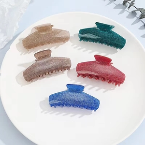 Five elegant frosted glitter hair claws in champagne, green, and navy on a tray