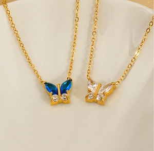 Close-up of butterfly pendants with blue and clear zircon crystals on golden necklaces