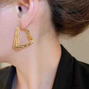 Close-up of 18k gold plated geometric layered triangle earrings worn by a model