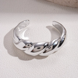Macro detail of silver twisted croissant bangle with polished reflective texture