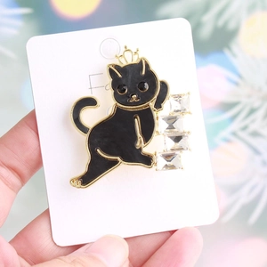 Close-up of a black cat brooch with golden crown and sparkling rectangle zircons