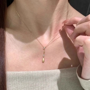 Minimalist Y-shaped brushed gold necklace with teardrop pendant and crystal accents