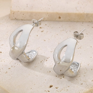 Minimalist silver-tone hollow figure-eight earrings on a textured stone background