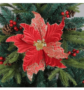 Close-up of red and gold velvet poinsettia with glitter on a festive Christmas tree branch