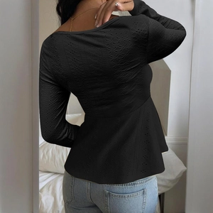 Macro shot of black long-sleeve knit top featuring detailed eyelet embroidery and pleated hem