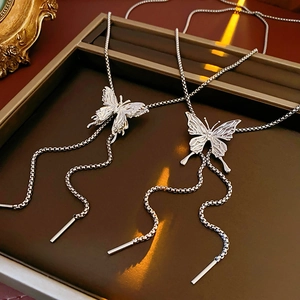 Detail of silver butterfly pendant necklaces with box chains on a vintage brown tray