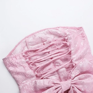 Détail macro d'une robe en jacquard rose avec laçage au dos et décoration d'un grand nœud
