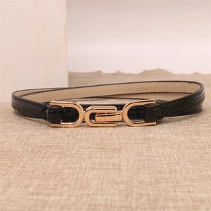 Detail of thin black glossy belt with golden geometric metal buckle on beige fabric