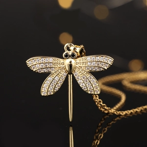 Macro shot of gold dragonfly pendant with sparkling white zircons and black gemstone eyes