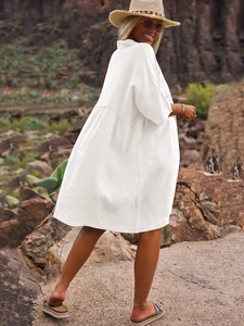 Detail of white loose-fit shirt dress with textured cotton fabric in outdoor resort setting