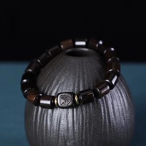 Détail d'un bracelet en bois de santal violet avec entretoises dorées sur céramique