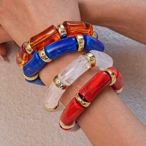 Detail of acrylic bangle set featuring amber blue and marble textures with gold link accents