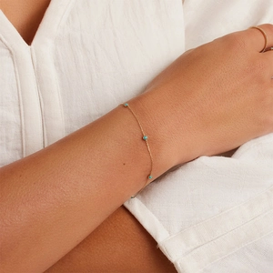 Minimalist gold link bracelet with turquoise beads on model wrist for a refined look