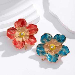 Vintage enamel flower brooches with colorful petals and crystal center on white backdrop