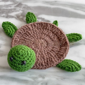 Detailed top-down view of a handmade crochet turtle coaster on a marble surface