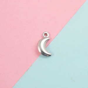 Macro shot of a silver crescent moon pendant for DIY jewelry making on a pastel background
