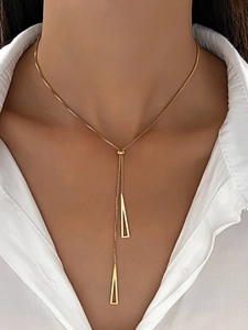 Detail view of a gold Y-shaped necklace with geometric hollow triangle pendants on a model