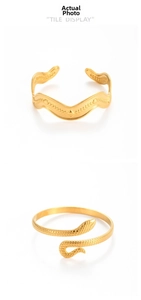 Detail of gold snake-shaped bangle and wavy textured cuff with geometric patterns
