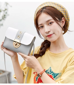 Detail of grey and white PU leather crossbody bag with golden metal lock and ring decoration