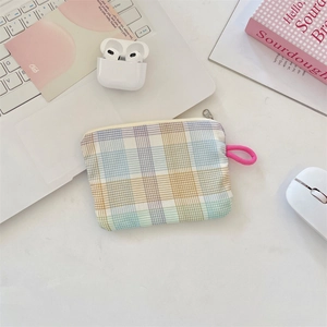 Flat lay of colorful plaid fabric coin purse with pink lanyard next to a laptop