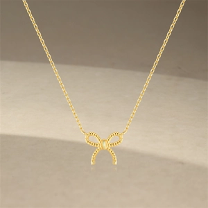 Détail de la texture de corde torsadée sur un pendentif noeud doré et chaîne fine