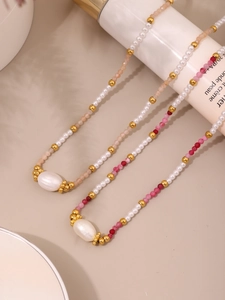 Dettaglio di collane di perle di conchiglia e pietre naturali colorate su fondo beige