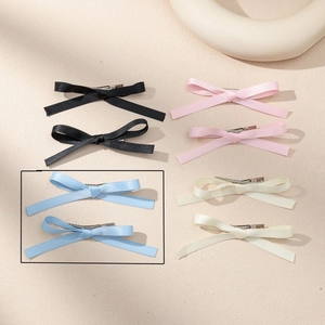 Detail of satin bow hair clips showing glossy silk texture and long ribbons in four colors