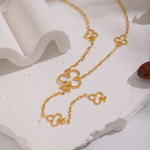 Bracciale dorato con ciondoli a fiori e catena a maglie su sfondo in pietra naturale