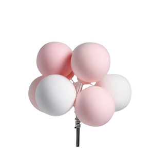 Pink and white balloon cake topper picks for birthday dessert decoration on a black rod