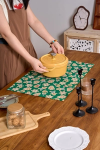 Detail of yellow ceramic stew pot on green festive Christmas cloth napkin in home setting