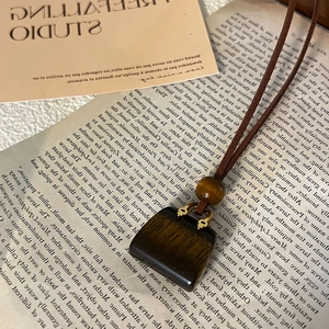 Macro detail of faux leather bag pendant with tiger eye stone and golden hardware